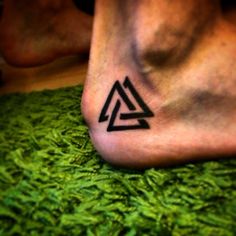 a close up of a person's foot with a triangle tattoo on the bottom