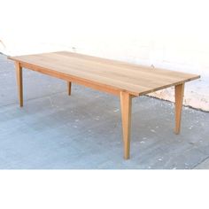 a wooden table sitting on top of a cement floor next to a white brick wall