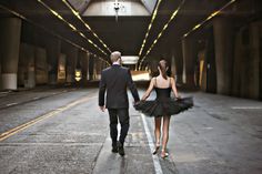 a man and woman are walking down the street holding hands while dressed in black tutu skirts