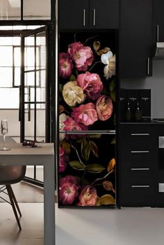 a kitchen with black cabinets and flowers on the door, next to a dining room table