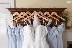 wedding dress hanging on wooden hangers with bride's dresses in blue and white