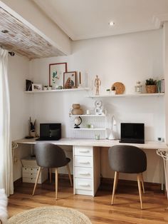 a white desk with two black chairs in front of it and shelves on the wall