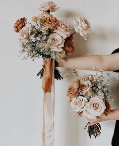 two women holding bouquets of flowers in their hands, one is tied to the wall