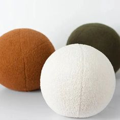 three different colored balls sitting next to each other on a white surface, one is brown and one is green