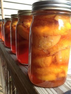 several jars filled with liquid sitting on top of a wooden table next to a window