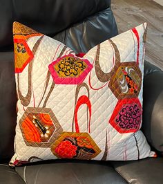 a decorative pillow on a black leather chair