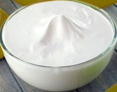 a glass bowl filled with whipped cream on top of a wooden table