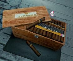 an open box of cigars on top of a table next to a brick wall