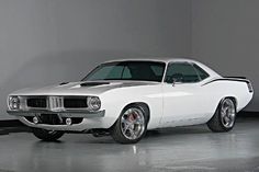 an old white muscle car parked in a garage next to a gray wall and floor