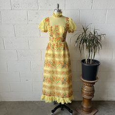 This 1970's vintage dress is made from a pastel yellow and orange colored, floral patterned cotton and features a ruffled collared, puffy sleeved, fit and flare, maxi length fit with a victorian style, split skirt in the back with a bow detailing the center of the back waistline. Zips up in back with a metal zipper to a keyhole opening below the neck which comes together with a hook and eye closure at the neck. The bow snaps into place at the waist over top. In excellent vintage condition with o Split Skirt, Ruffled Collar, 70s Vintage, Pastel Yellow, Metal Zipper, Victorian Style, Vintage Dress, Dress Clothes For Women, Victorian Fashion