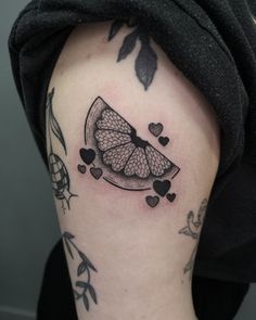 a black and white photo of a fruit tattoo on the right arm, with hearts around it