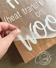 someone is cutting out some stickers on the side of a wooden sign that says heat transfer on it