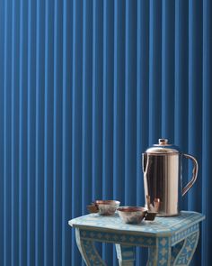 a table with two bowls and a pitcher on it next to a blue striped wall