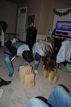 three people playing video games in a living room with bags on the floor and one person holding a wii controller