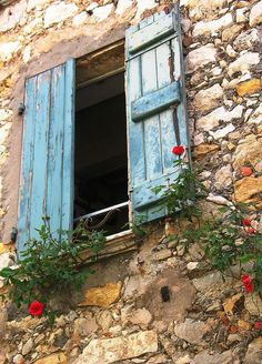 an old window with blue shutters and red flowers