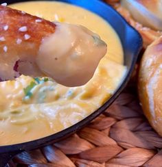 a person dipping some kind of food in a skillet with cheese and sauce on it