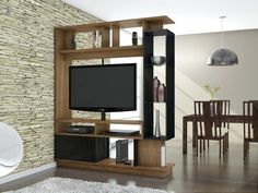 a living room with a television on top of a wooden entertainment center in front of a stone wall