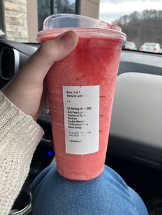 a person holding up a pink drink in their hand with a sticker on it