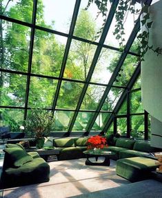 a living room filled with lots of furniture under a large glass ceiling covered in trees