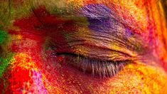 the eye of an elephant covered in colored powder is shown with its eyes closed and it's skin visible