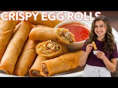 a woman standing in front of a white plate filled with egg rolls and dipping sauce