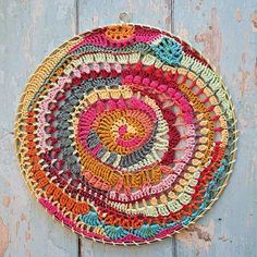 a colorful crocheted doily hanging on a wooden wall in front of a door