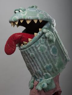 a stuffed alligator holding a red object in its mouth