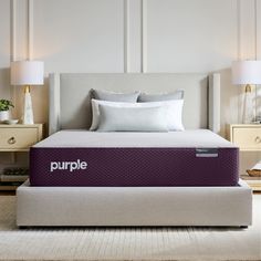 a purple mattress sitting on top of a bed next to two lamps and a night stand