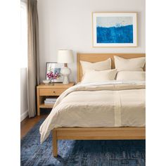 a bedroom with a bed, nightstands and pictures on the wall above it in blue tones