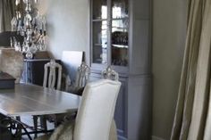 a dining room table with white chairs and chandelier