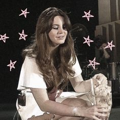 a woman sitting on the ground with her legs crossed and holding a basket in front of her