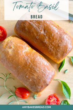 two loaves of bread sitting on top of a cutting board with tomatoes and basil