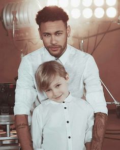 a man is helping a little boy put on his shirt in front of the camera