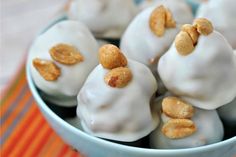 a bowl filled with white frosted donuts covered in nuts