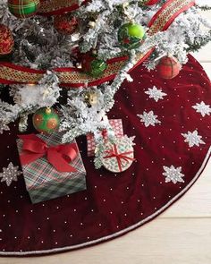 a christmas tree with presents under it on a red tableclothed placemat, decorated with snowflakes and ornaments