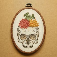 an embroidered skull with succulents and flowers on its head is shown in the shape of a frame