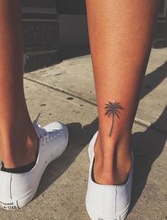 a person's foot with a small palm tree tattoo on the bottom of it