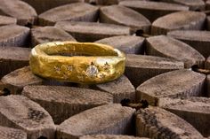 a close up of a gold ring on top of wooden blocks with diamonds in the middle