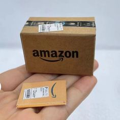 a hand holding a cardboard box with an amazon sticker on it