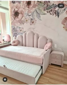 a pink daybed sitting in front of a floral wallpapered wall with flowers on it