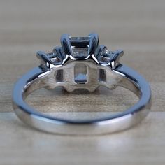 a close up view of a diamond ring on a wooden surface with the center stone missing