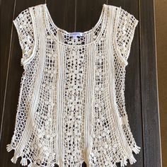 a crocheted white top hanging on a wooden door with an openwork design