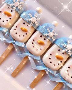 four snowman pops are arranged in rows with blue bows and white frosting on them