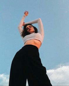 a woman in white shirt and black pants flying a kite