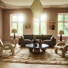 a living room with zebra print furniture and lamps on the wall, in front of two large windows