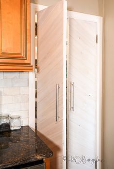 the corner of a kitchen with a wooden door and granite counter top next to an oven