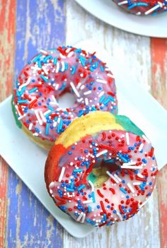 two donuts with sprinkles are on a white plate and one is red, white, and blue