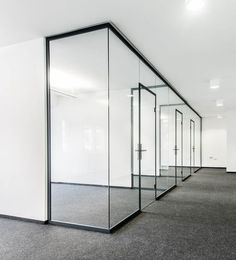 an empty room with glass partitions and carpeted flooring on the side wall