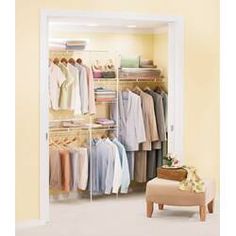 an open closet with clothes on hangers and a footstool in the corner