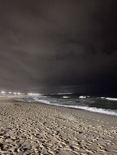 the beach is covered in footprints and dark clouds